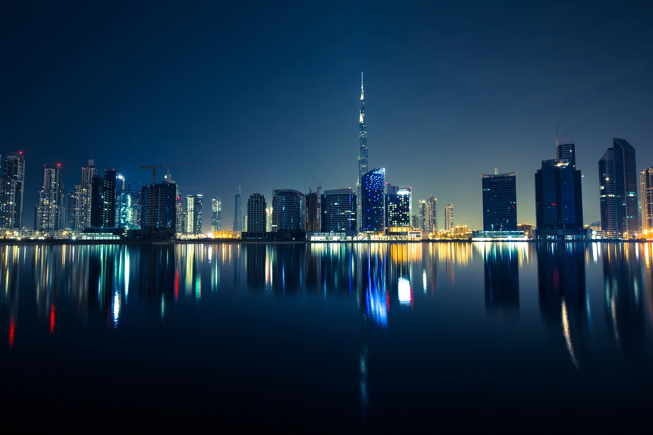 The Dubai skyline lit at night, the Burj Khalifa rising above the Business Bay waterfront