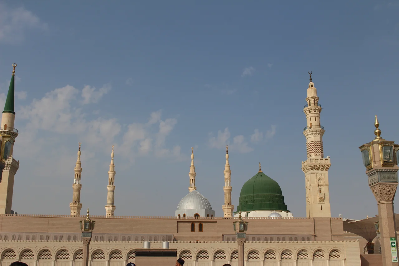 The Green Dome and minarets of the Prophet's Mosque in Madinah beneath a blue sky